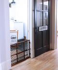 Position And Lock Adjustable Wood Baby Gate For Farmhouse Style Homes next to a black laundry room door
