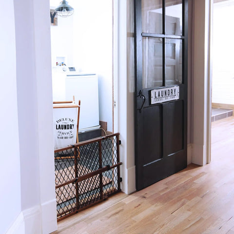 Position And Lock Adjustable Wood Baby Gate For Farmhouse Style Homes next to a black laundry room door