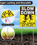 Slow Down Children At Play Safety Signs 2 Pack 17 By 13 Inch Double Sided Corrugated Plastic With H Metal Stakes installed in grass