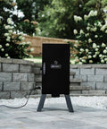 Electric Vertical BBQ Smoker With Analog Temperature Control 30 Inch Black Unit Featuring 535 Sq In Of Cooking Space Chrome Smoking Racks Removable Wood Chip Tray Perfect For Up To 3 Chickens Or 2 Turkeys Or 3 Racks Of Ribs on a patio