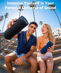 Two people sitting on steps outdoors holding Roar 3 Bass-Boosted Portable Bluetooth Speaker With 20W Thumpin Bass, JIKE Bass Enhancement.