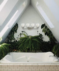Belton Four Light Wall Bath Vanity Light Fixture With Brushed Nickel Finish, Clear Seeded Glass Shades above a bathtub in bright bathroom