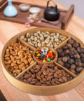 Top Grade Bamboo Serving Platter With Built-In Dividers, 12 Inch Snack Board For Fresh Fruit And Nuts filled with assorted nuts and candies.