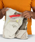 Man holding Duro 6L Running Hydration Vest with Hydraulics Soft Flasks in sandy grey, showing front pockets and stabilizers