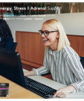 Woman smiling while using a computer with She's Obsessed Vitality Complex for hormone balance and mood support visible in corner