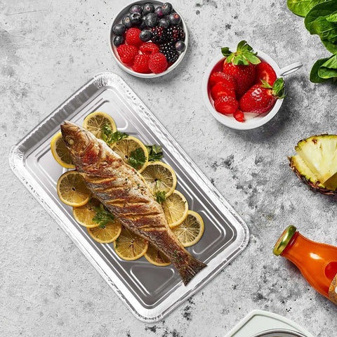 Whole fish on 50 Pack Half Size Aluminum Pans Disposable Cookie Sheets with lemon slices, berries, and orange juice on side, 12.7 x 7.9 inches.