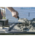 Builder using London Style Pro Grade Brick Trowel With DuraSoft Handle For Brickwork Blockwork And Stonework Ten And One Half Inch By Four And Three Quarters Inch Forged High Carbon Steel Made In USA Masonry Tool to scoop mortar