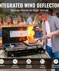 Person grilling on Portable Three Burner Propane Camping Stove With Regulator Push Button Ignition Adjustable Burners And Wind Guards For Car Trips Picnics And Outdoor Cooking 20400 BTUs Lightweight About Ten Pounds.