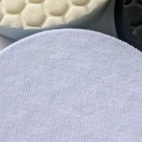 Close-up of three different 6-inch foam buffing pads in white, honeycomb, and black textures for car detailing.