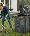 Woman gardening near 80 Gallon Outdoor Compost Bin With Top Lid And Bottom Door Aerating Design, weatherproof black plastic container.