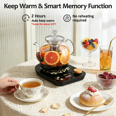 Glass electric tea maker with infuser, displaying herbal tea brewing; tea set on table with fruit and pastries