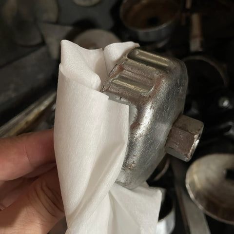 Close-up of Top Notch Heavy Duty Industrial Shop Towels Multipurpose Cleanroom Wipes used for cleaning a metal tool.