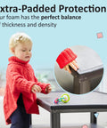 Top Shelf Baby Proofing Edge And Corner Guard Protectors Featuring Twenty Feet Of PreTaped Shock Absorbing Rubber Foam With Eight Thick Furniture Bumpers For No Sweat Toddler Safety And Quick Peel Off Cleanup, showing corner guard on table.