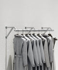Industrial Pipe Wall Shelf Rustic Metal Display Rack For Clothing And Laundry Garment Bar mounted on white wall