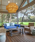 Epic Large Gold Boho Rattan Chandelier With 8 Lights hanging over a porch seating area with outdoor view