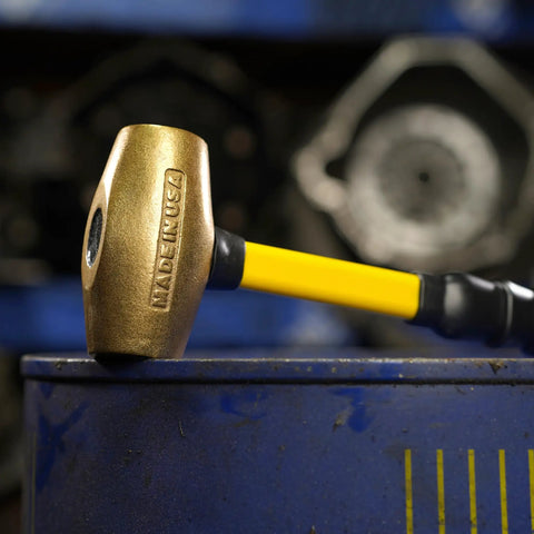 14 Inch Brass Hammer With Fiberglass Handle 2 Pound Non Sparking Tool Double Faced Head USA Made resting on blue surface