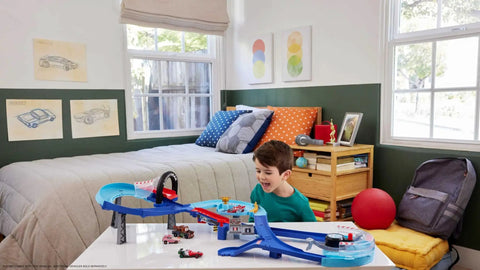 Child playing with GRC Jumping Raceway Track Set With Kid Powered Booster And Lightning McQueen And Francesco Bernoulli Cars in bedroom