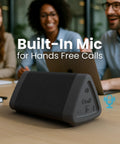 Angle 3 4th Gen Portable Bluetooth Speaker With 12W Stereo Sound 24 Hour Playtime Rich Bass 100 Foot Wireless Range Waterproof shown on desk in meeting room with built-in mic for hands-free calls.
