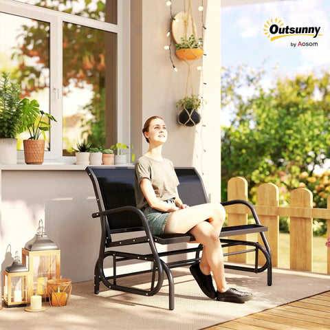 Woman sitting on Two Person Outdoor Glider Bench Swing Loveseat for Patio Porch and Garden with Double Rocking Chair and Powder Coated Steel Frame Built For Cozy Hangouts Water Resistant Quick Dry Sling Fabric UV Resistant Black by a window.