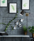 Dope Modern Industrial Swing Arm Wall Sconce In Matte Black With Brass Accents installed over office desk with plants and artwork