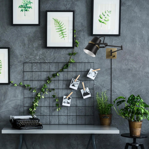 Dope Modern Industrial Swing Arm Wall Sconce In Matte Black With Brass Accents installed over office desk with plants and artwork