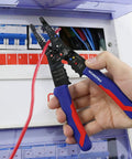 Hand holding All-In-One 8-Inch Wire Stripper And Multi-Tool Cutter for stripping, cutting, and crimping wires in electric panel