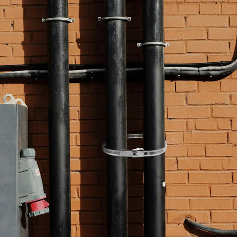 Heavy Duty Stainless Steel Pex Clamps With Quick Release Design For Plumbing Fittings securing pipes against a brick wall