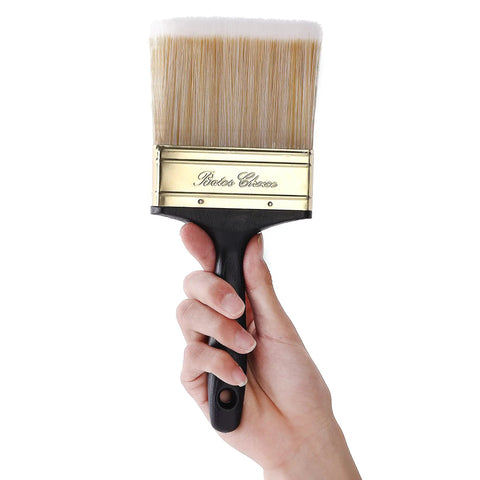 Person holding a 4-inch wide brush from Workhorse Deck Stain Brush Set for Wood Projects 4 Pack with brass ferrule and ergonomic handle.