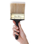 Hand holding 4 Inch Soft Tip Paint Brush For Walls And Trim With Pro Grade Synthetic Bristles That Hold More Paint For Fewer Strokes.