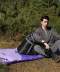 Person sitting on Roomy 32F Sleeping Bag For Adults Kids And Teens All Season Camping Gear For Winter Cold Weather Lightweight Yet Warm 86 Inch Long With Three Zippers Perfect For Travel And Outdoors For Campouts
