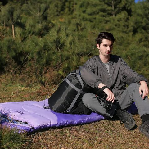 Person sitting on Roomy 32F Sleeping Bag For Adults Kids And Teens All Season Camping Gear For Winter Cold Weather Lightweight Yet Warm 86 Inch Long With Three Zippers Perfect For Travel And Outdoors For Campouts