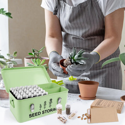 Gardener potting plant with open 60 Slot Metal Seed Storage Organizer with lid, safety locks, envelopes, and labels on table