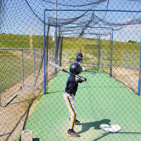 Child practicing baseball in Heavy-Duty Backyard Batting Cage Net 55x12x12ft Weatherproof Polyester Construction for All Weather