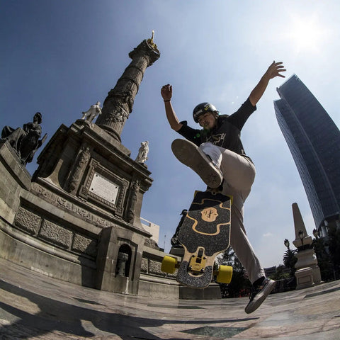 Skater performing a trick with Stimulus 70mm 86A Freeride Longboard Wheels Yellow Set of 4 in urban setting.
