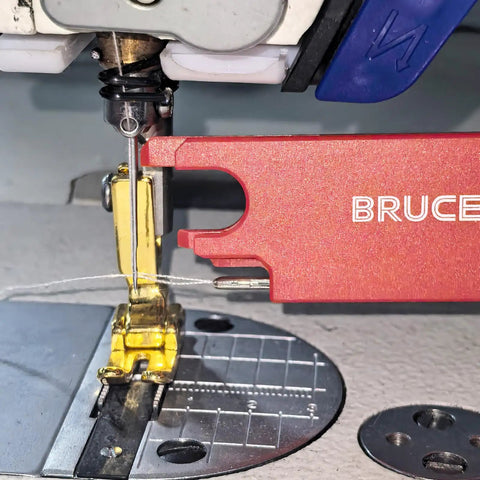 Close-up of a sewing machine with Four In One Automatic Needle Threader with quick threading magnifier lens in action.