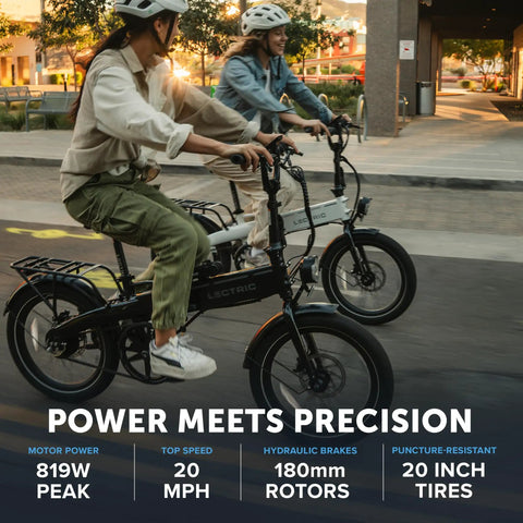Two adults riding XP Lite2 Folding Electric Bike For Adults, Arctic White, on city street, showcasing 819W peak power and hydraulic brakes.
