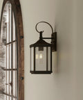 Gibbes Street Collection 1 Light Outdoor Wall Lantern in Antique Bronze with clear beveled glass mounted on wall indoors.