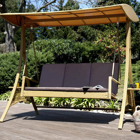 Outdoor canopy swing bench with cushion on wooden deck in garden setting