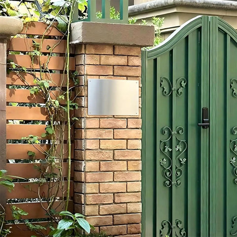 Brick wall with blank aluminum sign near green gate, representing Built Tough Aluminum Safety Sign 8x12 Inch For SDS Station.