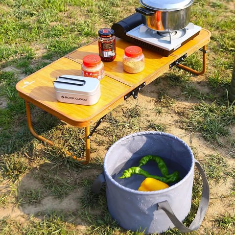Ultralight Portable Camping Table Foldable Three Folding Beach Table For Camping Hiking Garden Outdoor Picnic With Carry Handle And 60 Lbs Load Capacity 35.4 By 15.7 By 10.2 Inches in use with food items on grass