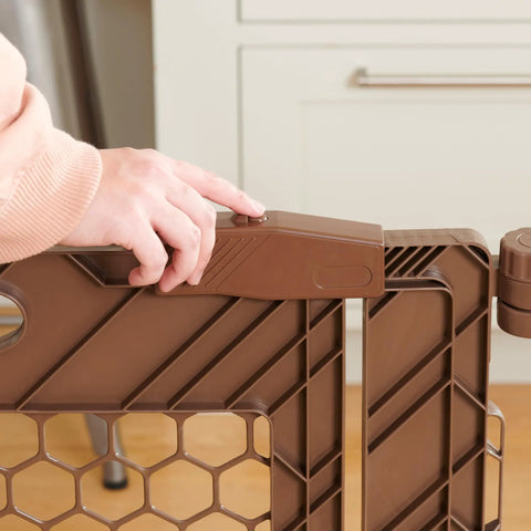 Close-up of brown 192-Inch Ultra Wide 2-In-1 Baby Gate And Play Yard With Door lock mechanism being operated.