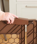 Close-up of person operating latch on brown baby gate, part of Super Wide 192 Inch Baby Gate And Play Yard System.