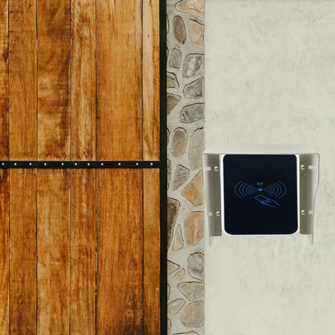 Beefy Iron Roof Cover for Electric Vehicle Charger Keeps Your Level 2 Wall Box Sweet by Blocking Rain Snow and Sun Damage while Offering Universal Fit for Standard Stations and Rock Solid Safety, shown on a wall with wooden and stone panels.