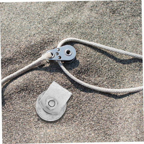 Cast-iron V-type grooved garage door roller with mounting plate and white rope on sand.