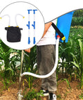 Person using Backpack Spreader Sprayer For Garden And Farm Adjustable Output Granular Manure Applicator with PVC handle in a field.