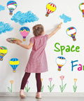 Child decorating wall with Totally Colorful Hot Air Balloon Cutouts Set With 54 Paper Shapes And 60 Glue Dots
