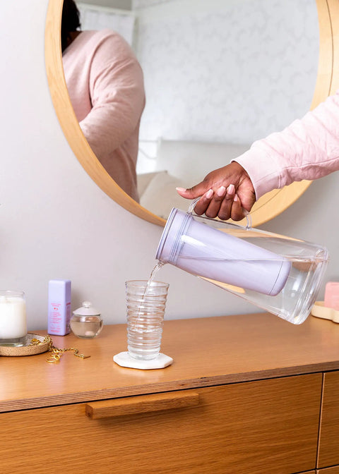 Person pouring from Water Filter Pitcher 10-Cup BPA Free Wisteria for Everyday Protection From Bacteria, Parasites, Microplastics.