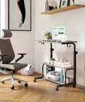 Unwind And Handle Daily Grind At This Grey Oak Rolling Standing Desk With Height Adjustable Top Smooth Gliding Wheels Grab And Go Mobility Side Hooks And Roomy Storage Shelves For Your Home Office Setup, featuring laptop on rolling cart with plants.