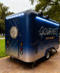 Solid As A Rock Mobile Food Trailer And Rolling Cart Combo Crafted For Coffee Ice Cream Sales Quick Hustle Setup That Grinds Like A Dream On Busy Weekends showing blue trailer rear with gourmet graphics.