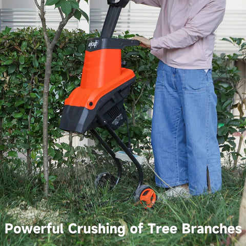 Person using Beast 1800W Electric Wood Chipper Shredder for yard cleanup, cutting branches near a tree.
